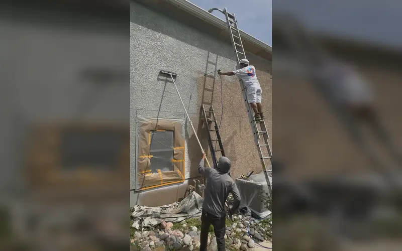 Painters masking windows and prepping a stucco exterior