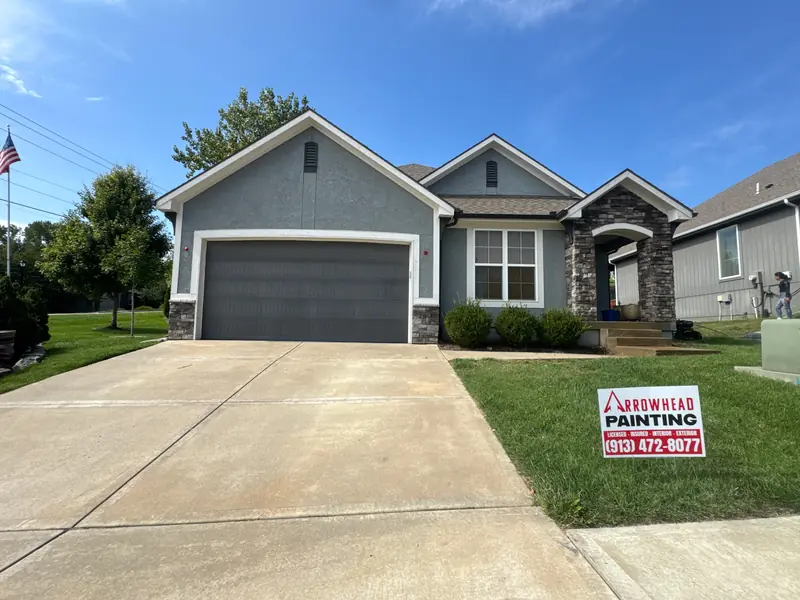 Freshly painted gray Kansas City home with an Arrowhead Painting yard sign