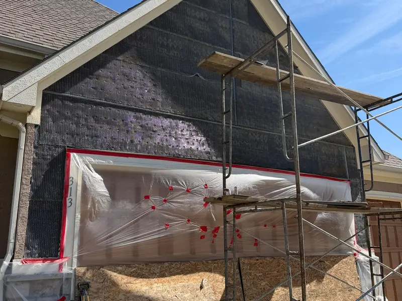 Siding replacement in progress on a Kansas City home with scaffolding and house wrap