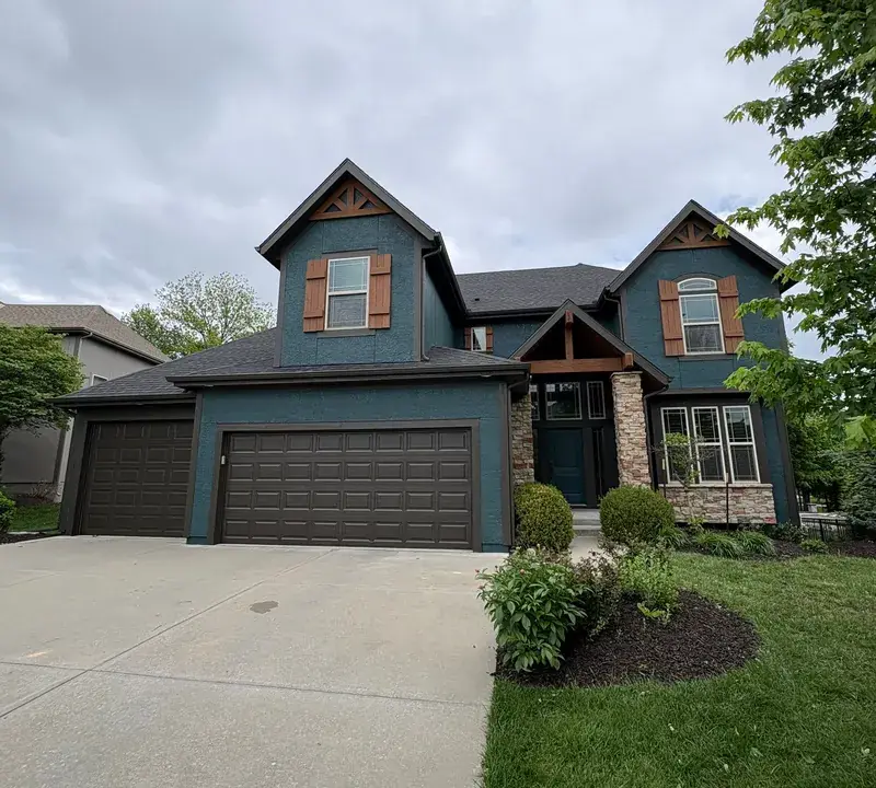 Two-story home painted deep teal with cedar accents