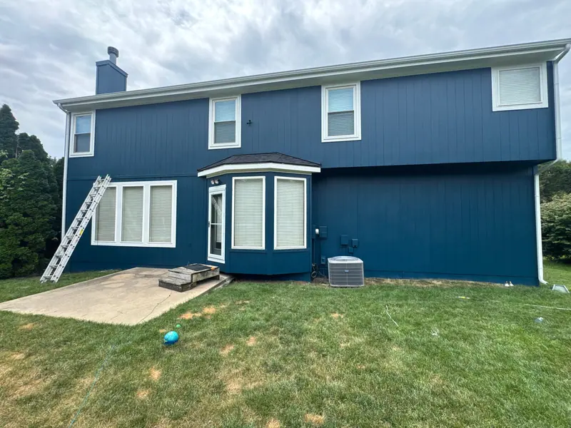 Crew painting a two-story home deep blue