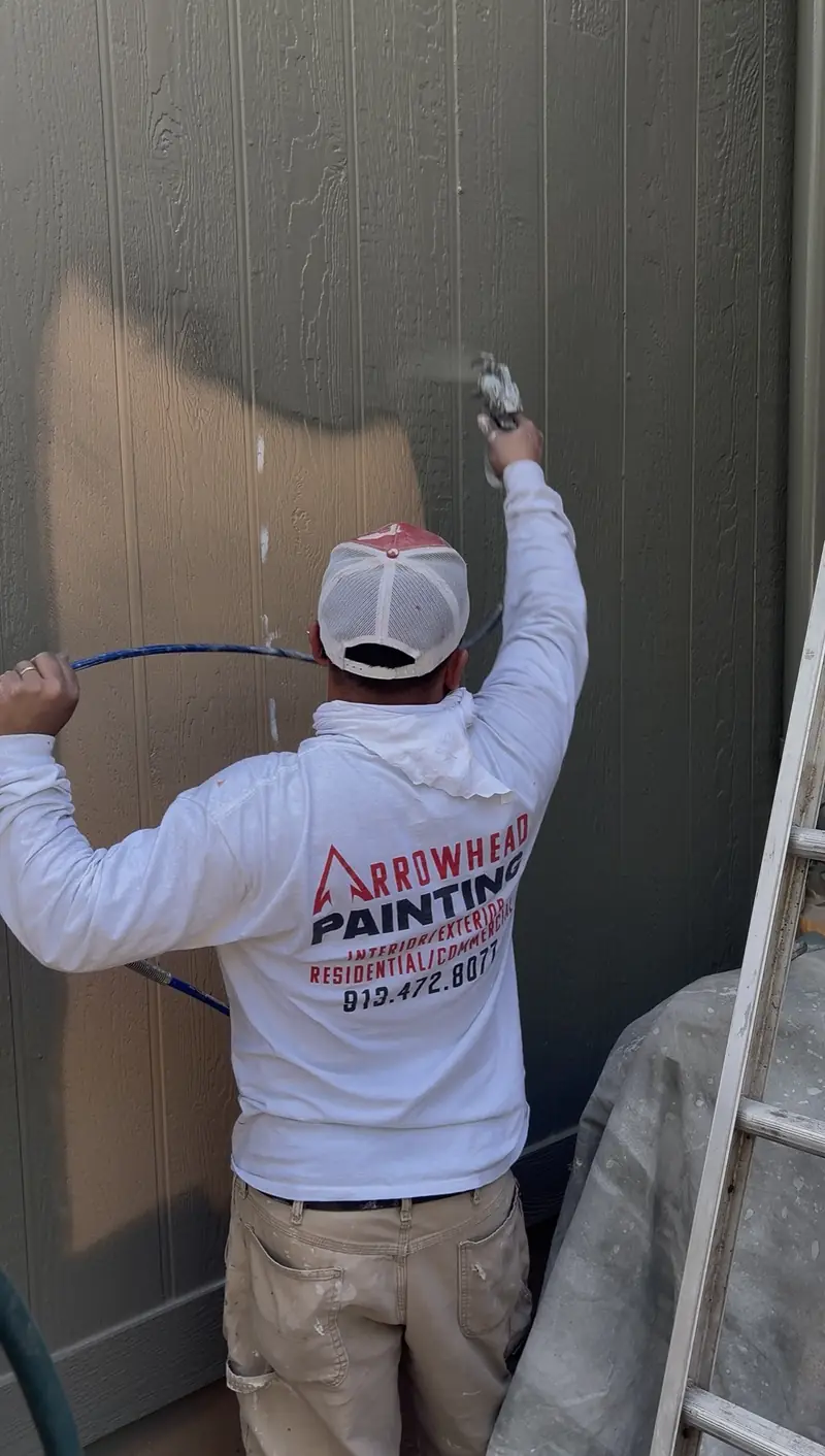 Arrowhead painter brushing fresh paint onto siding