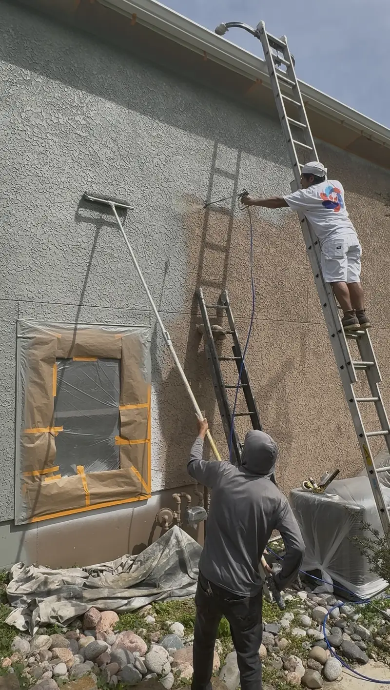Painters masking windows and prepping a stucco wall