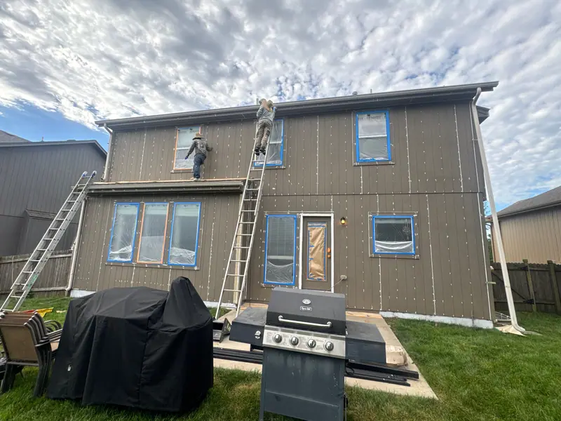 Crew painting the back of a two-story home
