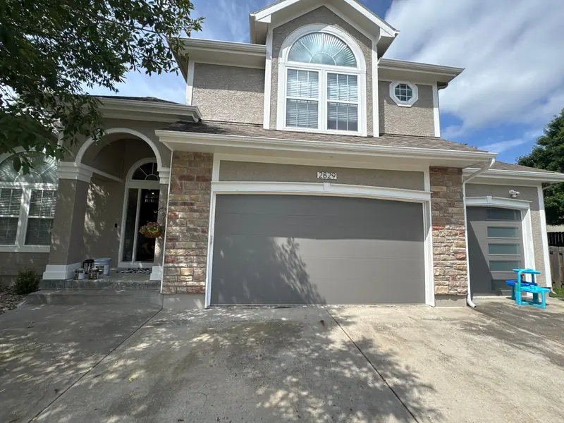 Two-story home with stone accents and an arched window