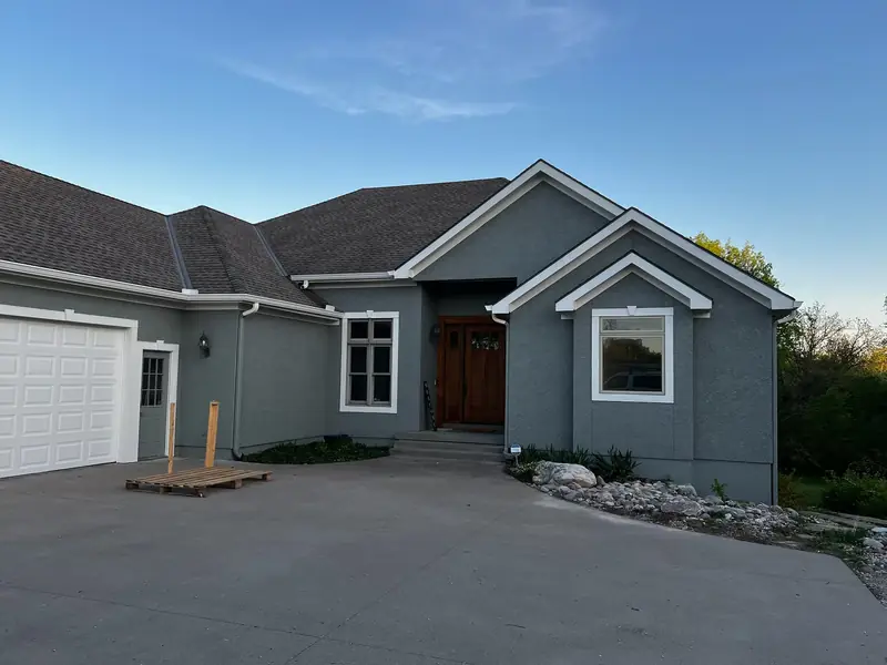 Gray stucco ranch home with white trim after an exterior repaint