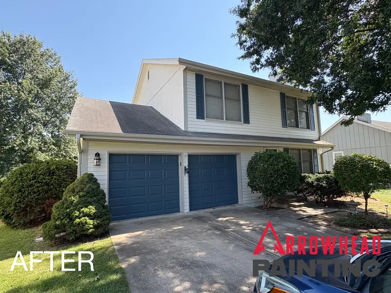White colonial with navy blue garage doors as an accent color