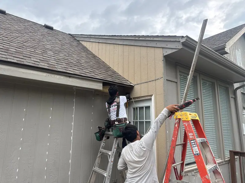 Crew replacing siding on a two-story home